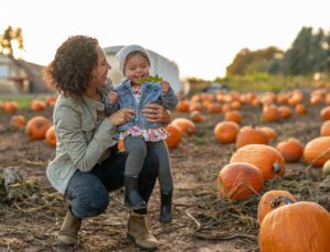 mother and child laughing at pumpkin patch