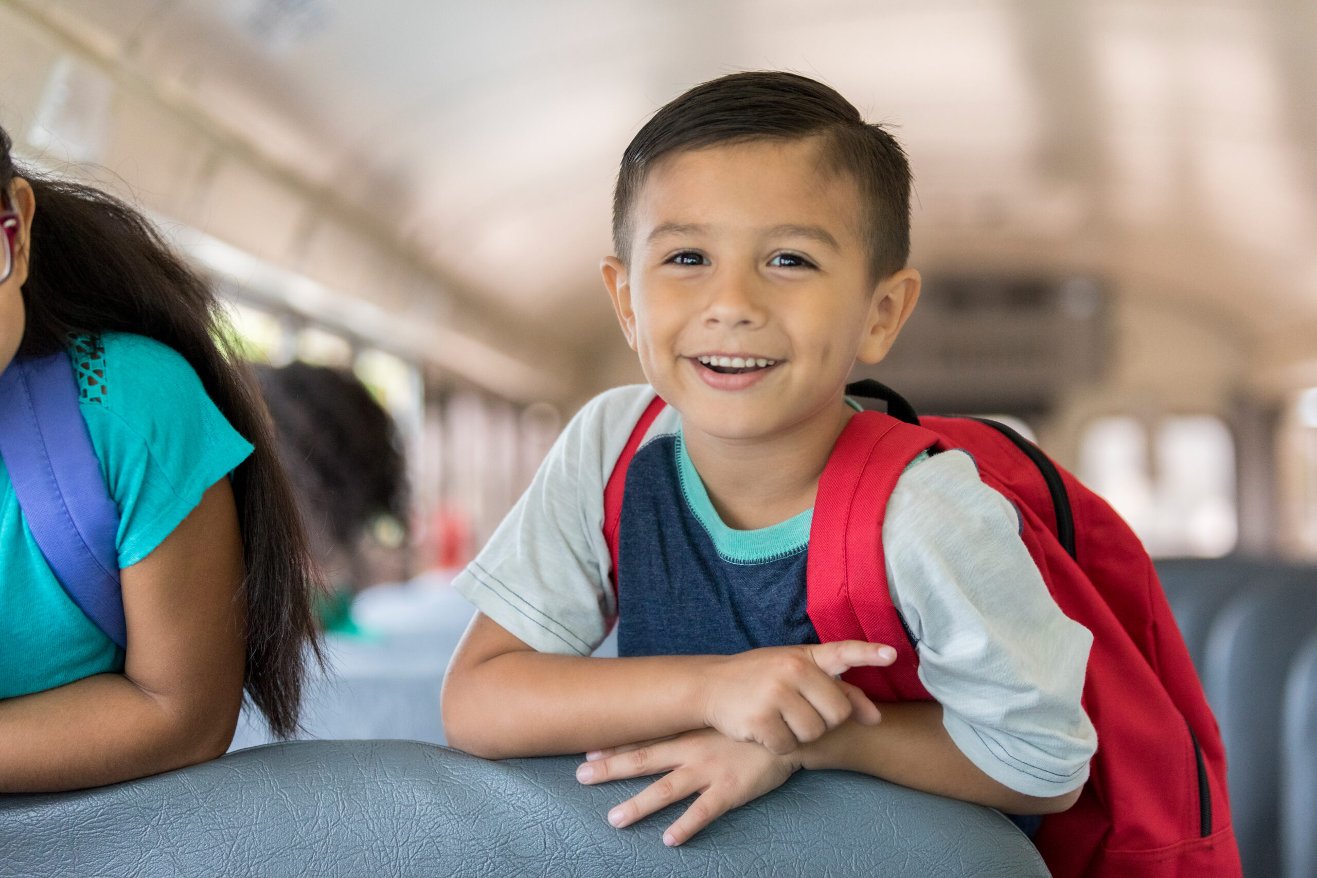 Boy riding a school bus to kindergarten.